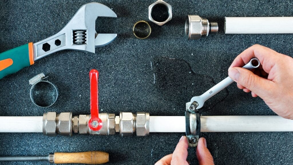 Plumber repairing a pipe valve with an adjustable wrench in Union City