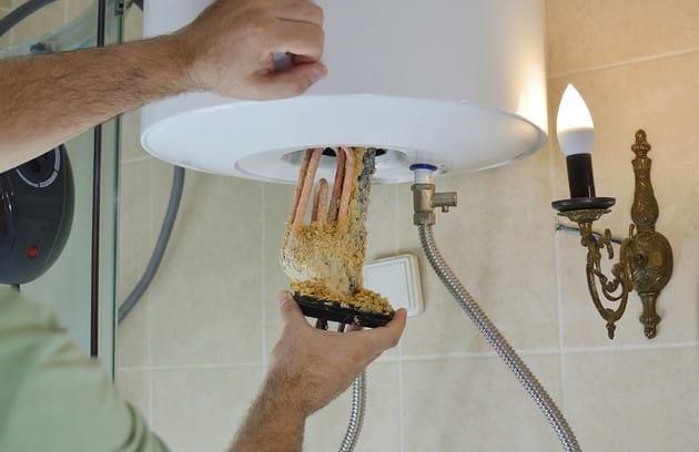 Technician removing mineral buildup from a water heater in Union City