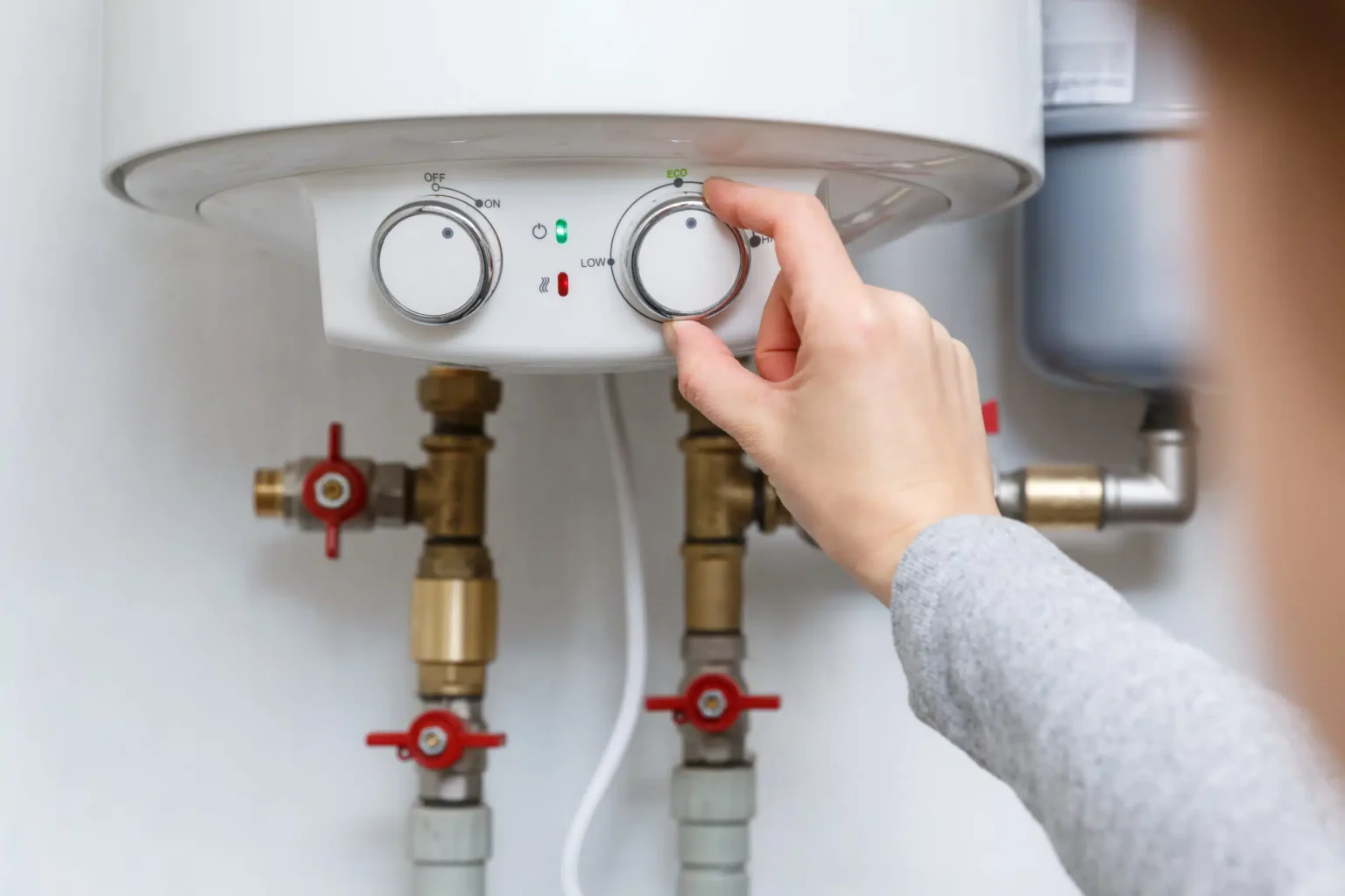 Homeowner adjusting the temperature controls on a water heater in Union City